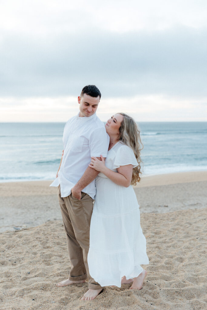 engaged couple in monterey on sand dunes at sunset