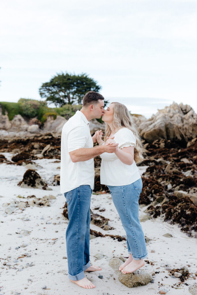 couple wearing jeans and white shirts on beach in Monterey