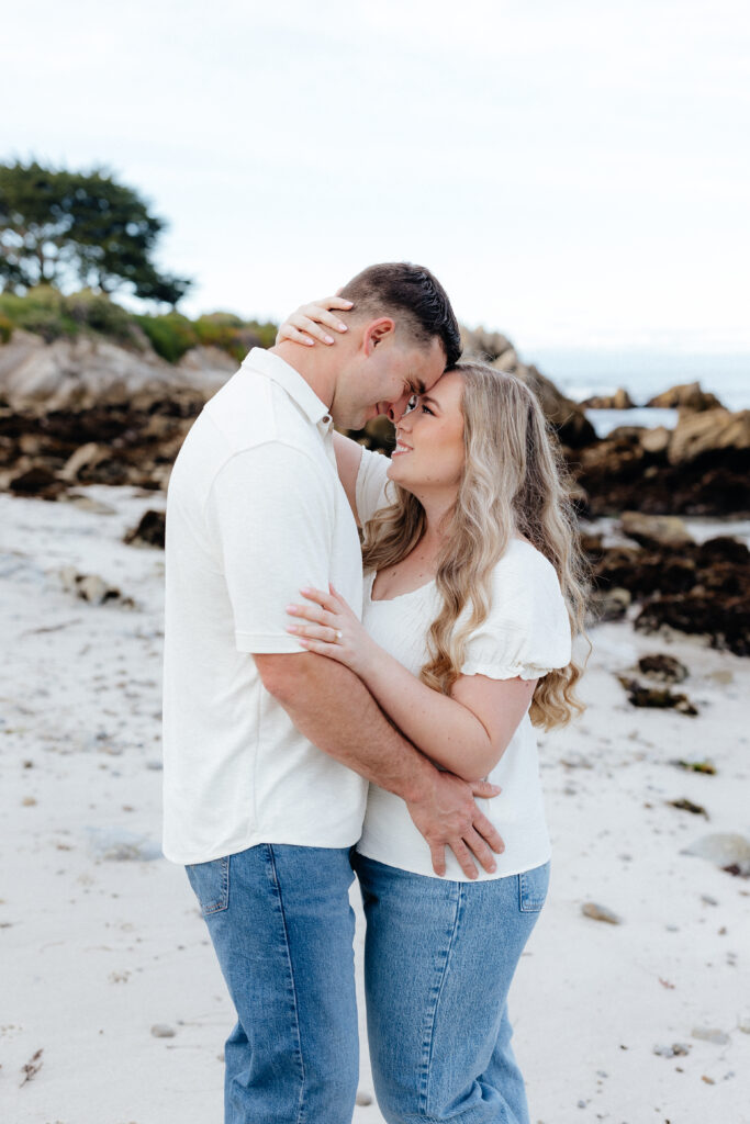 couple wearing jeans and white shirts on beach in Monterey