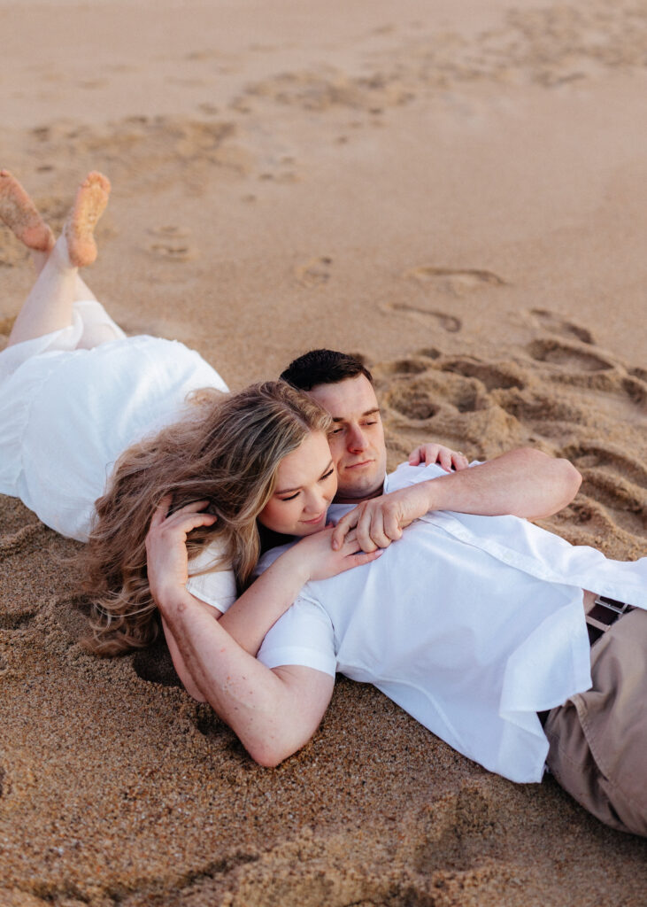 engaged couple in monterey on sand dunes at sunset