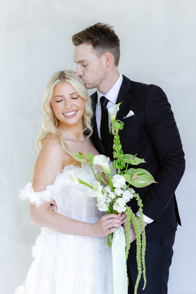 Bride and groom in white chapel with greenery and hydrangeas