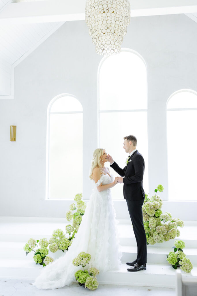 Bride and groom in white chapel with greenery and hydrangeas