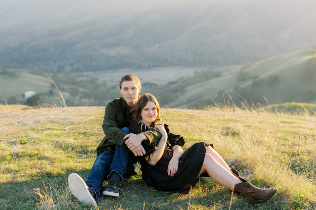 Man and woman sitting on grass for engagement photos