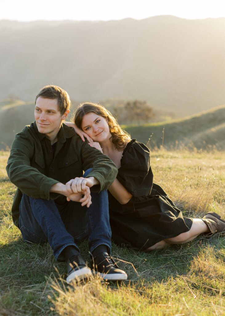 Man and woman sitting on grass for engagement photos