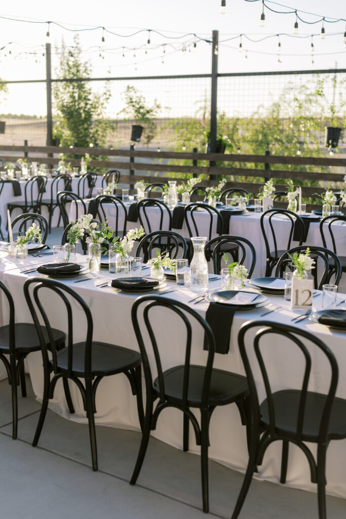 Long tables with black and white floral centerpieces at The Margaux outdoor wedding reception.