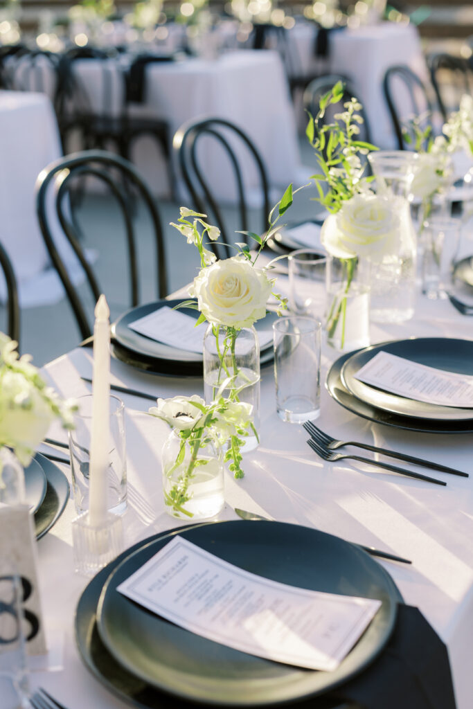 Long tables with black and white floral centerpieces at The Margaux outdoor wedding reception.