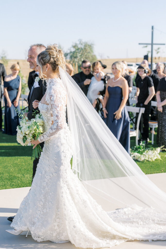 Outdoor ceremony setup at The Margaux wedding venue with modern circular arch and white floral aisle décor.