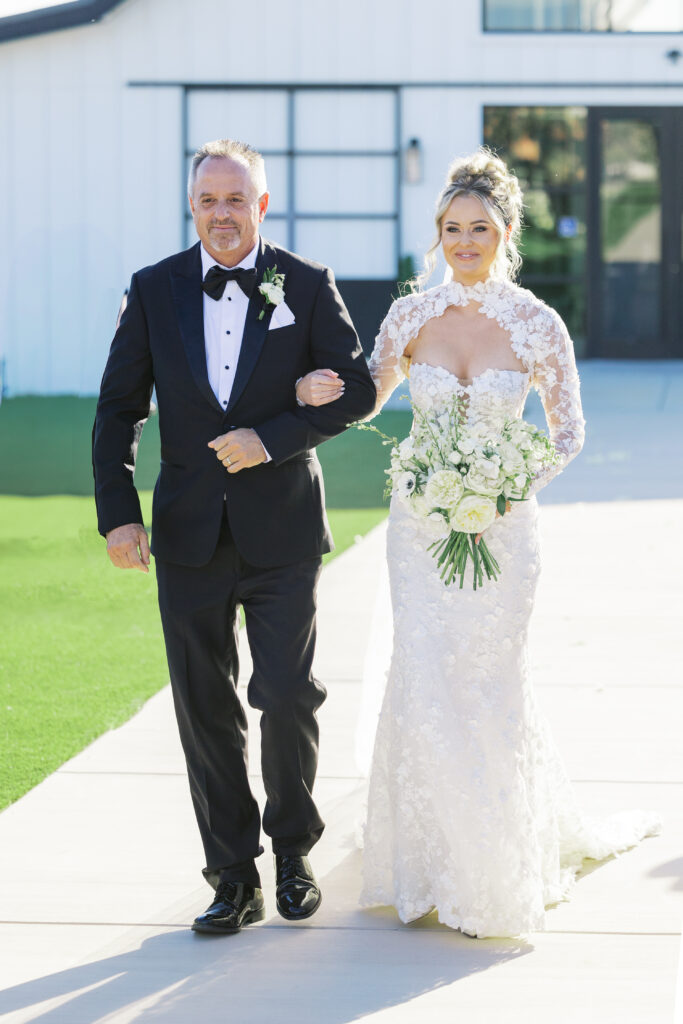 Outdoor ceremony setup at The Margaux wedding venue with modern circular arch and white floral aisle décor.