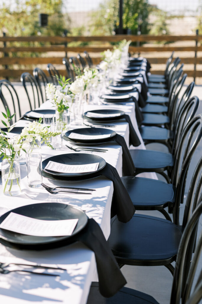 Long tables with black and white floral centerpieces at The Margaux outdoor wedding reception.