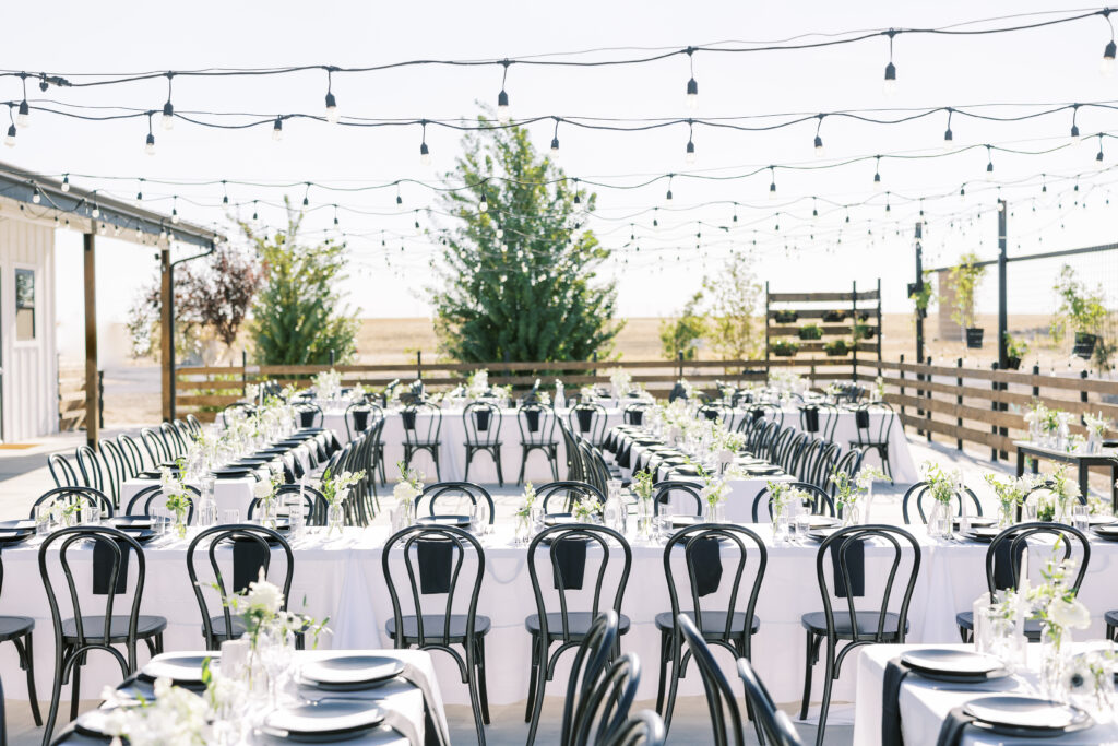 Long tables with black and white floral centerpieces at The Margaux outdoor wedding reception.