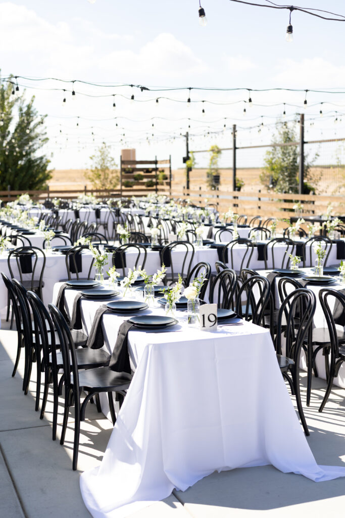 Long tables with black and white floral centerpieces at The Margaux outdoor wedding reception.