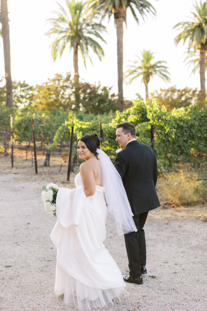 Couple walking hand in hand along palm tree lined driveway at The Palm Event Center