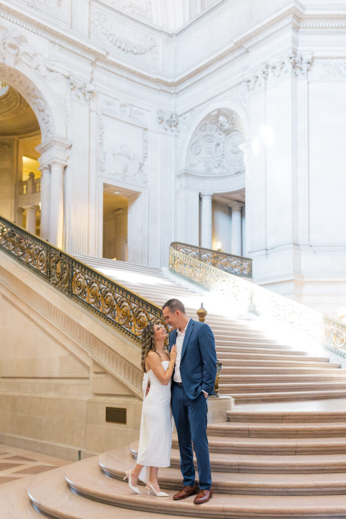 Elegant engagement portrait of couple in front of marble interior at SF City Hall