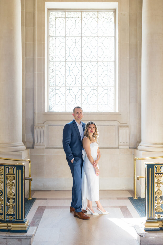 Elegant engagement portrait of couple in front of marble interior at SF City Hall