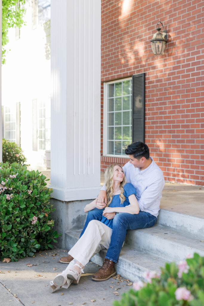 couple sitting in front of brick building during a natural engagement photos